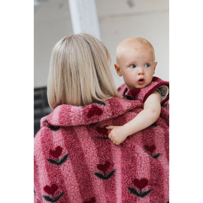 Lulu Baby bodywarmer cherry: baby wordt vastgehouden door volwassene met zichtbaar hartjespatroon op roze fleecestof