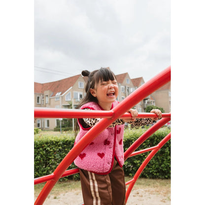 Alwero X Salty Tyb Junior Bodywarmer Bubble in roze, gedragen door meisje op rode speeltoestel in buurt