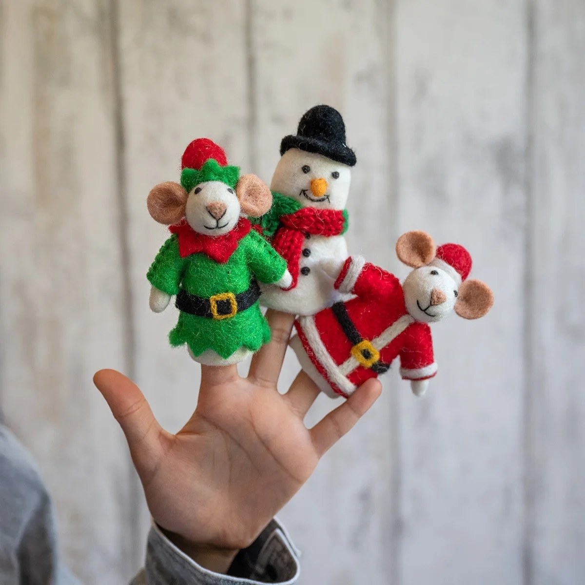 Sjaal met Verhaal vingerpopjes sneeuwpop: hand toont drie vilten poppetjes in winteroutfits op witte achtergrond