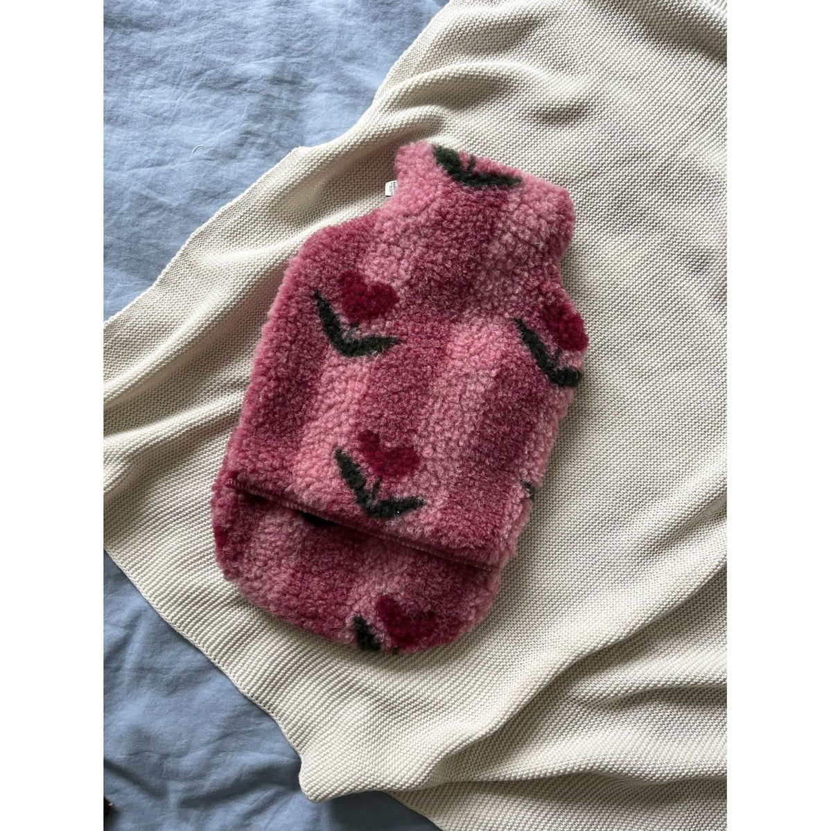 Alwero kruikenzak van geruwde wol in Thumbled Cherry, uitgevouwen op crèmekleurig knitwear met zwarte stiksels zichtbaar