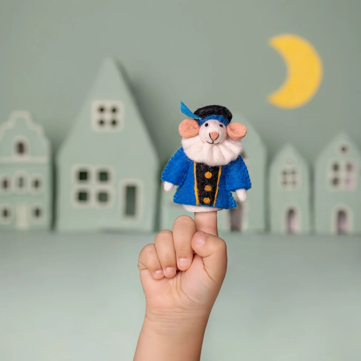 Sjaal met Verhaal vilten vingerpopje Pietermuis in blauwe jas, gehouden op kindervingers voor huizen en maan