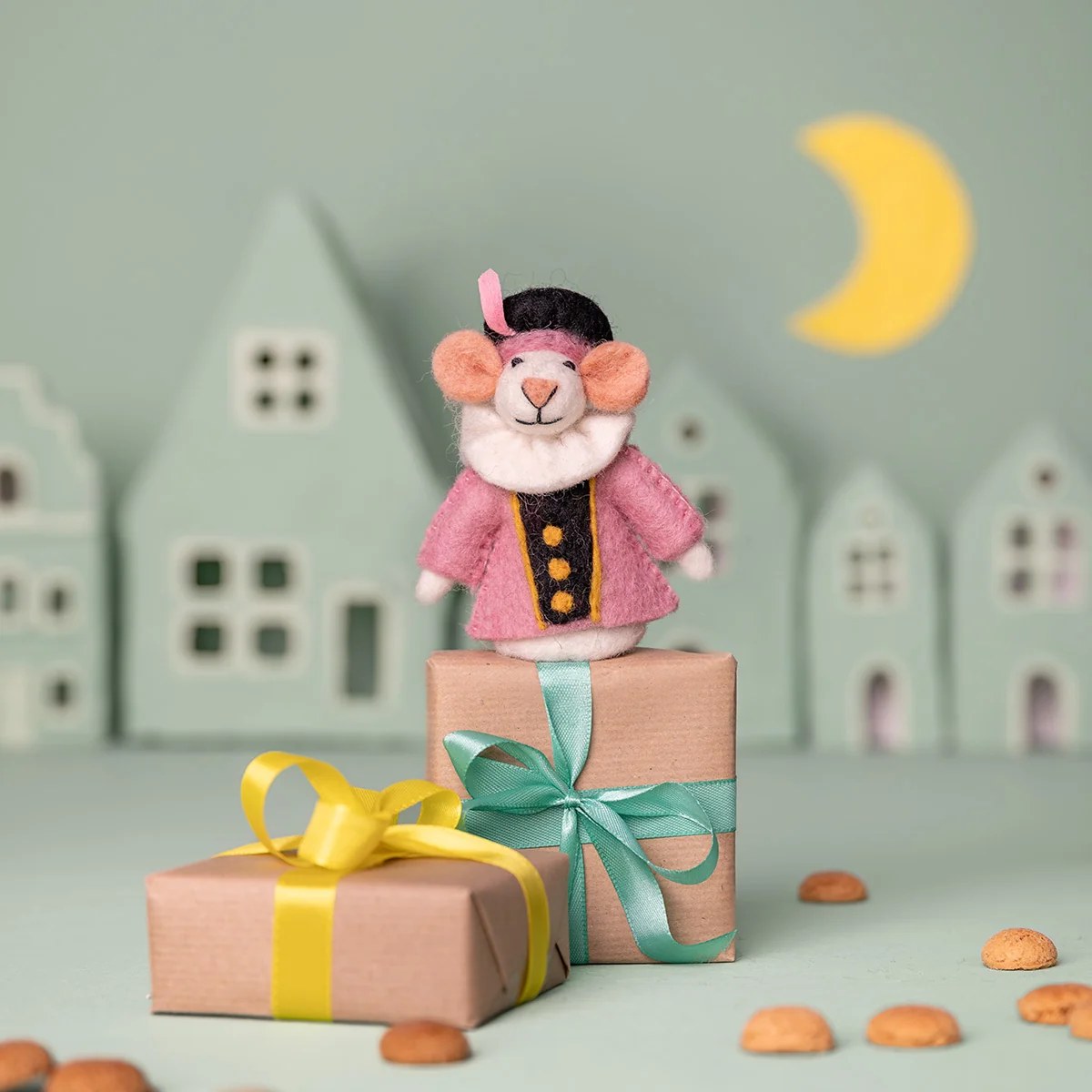 Sjaal met Verhaal vingerpopje muis in roze outfit op geschenkdozen met lint in sprookjesstad decor.