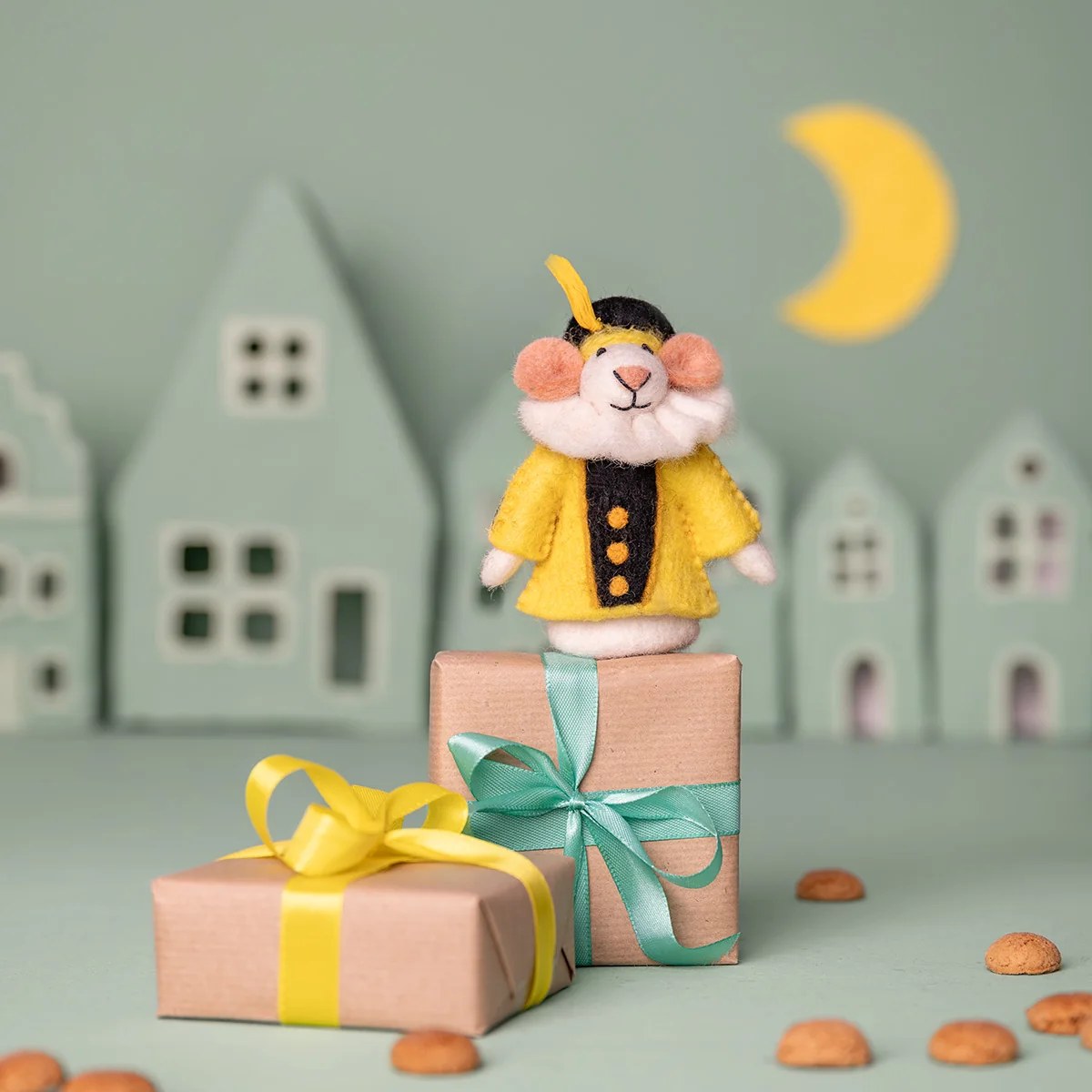Sjaal met Verhaal vilten vingerpopje muis in geel jasje, staand op geschenkdoos met lint in miniatuurdorp