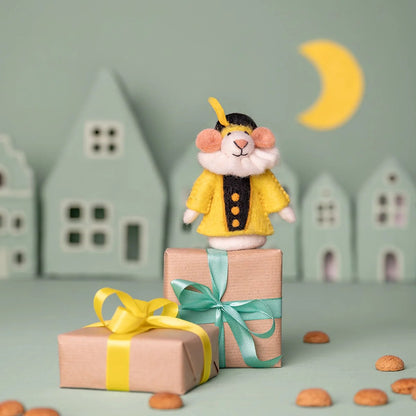 Sjaal met Verhaal vilten vingerpopje muis in geel jasje, staand op geschenkdoos met lint in miniatuurdorp
