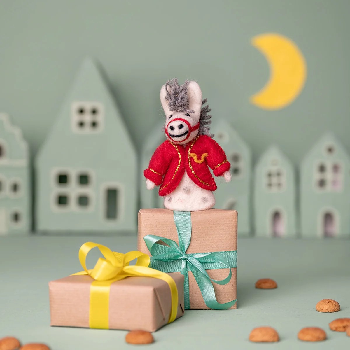 Sjaal met Verhaal vilten vingerpopje paard van Sintermuis in rood jasje, staand op geschenkverpakking tussen huisjes en maan.