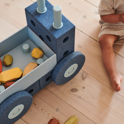 MODU 3-in-1 baby walker Deep Blue in gebruik: bovenaanzicht van loopwagen met speelgoedblokken in opbergbak en kind ernaast op houten vloer