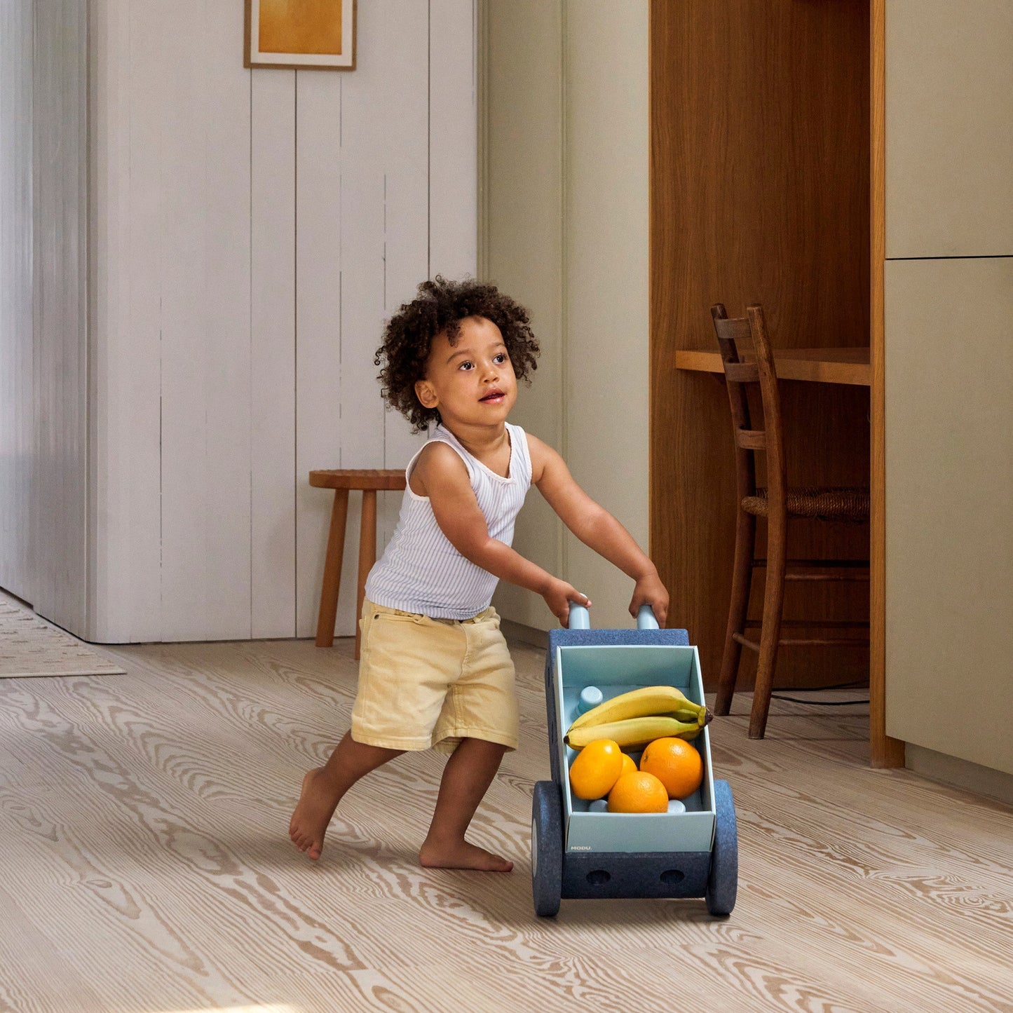 MODU 3-in-1 baby walker deep blue met fruit, gebruikt door klein kind in modern interieur
