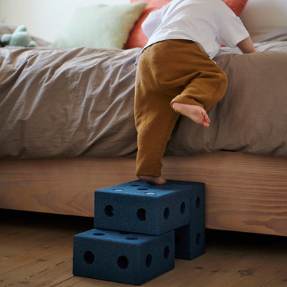 MODU 3-in-1 baby walker deep blue trapje in gebruik: peuter klimt op gestapelde blokken naast bed