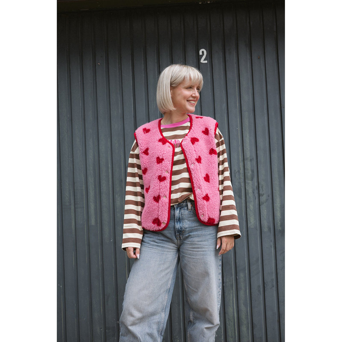 Alwero bodywarmer dames met hartjes, roze wollen vest over gestreept shirt, vooraanzicht tegen donkere achtergrond