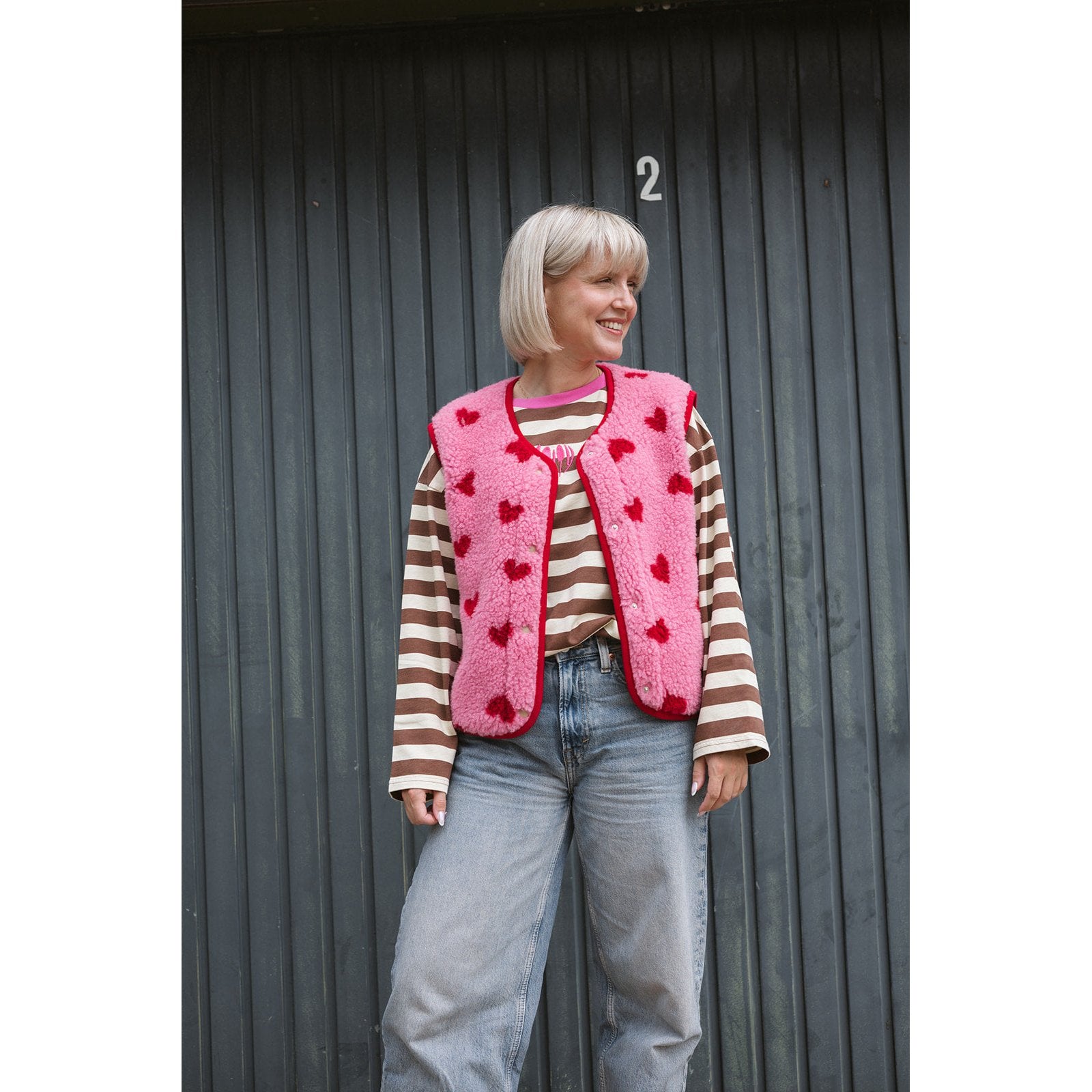 Alwero bodywarmer dames met hartjes, roze wollen vest over gestreept shirt, vooraanzicht tegen donkere achtergrond