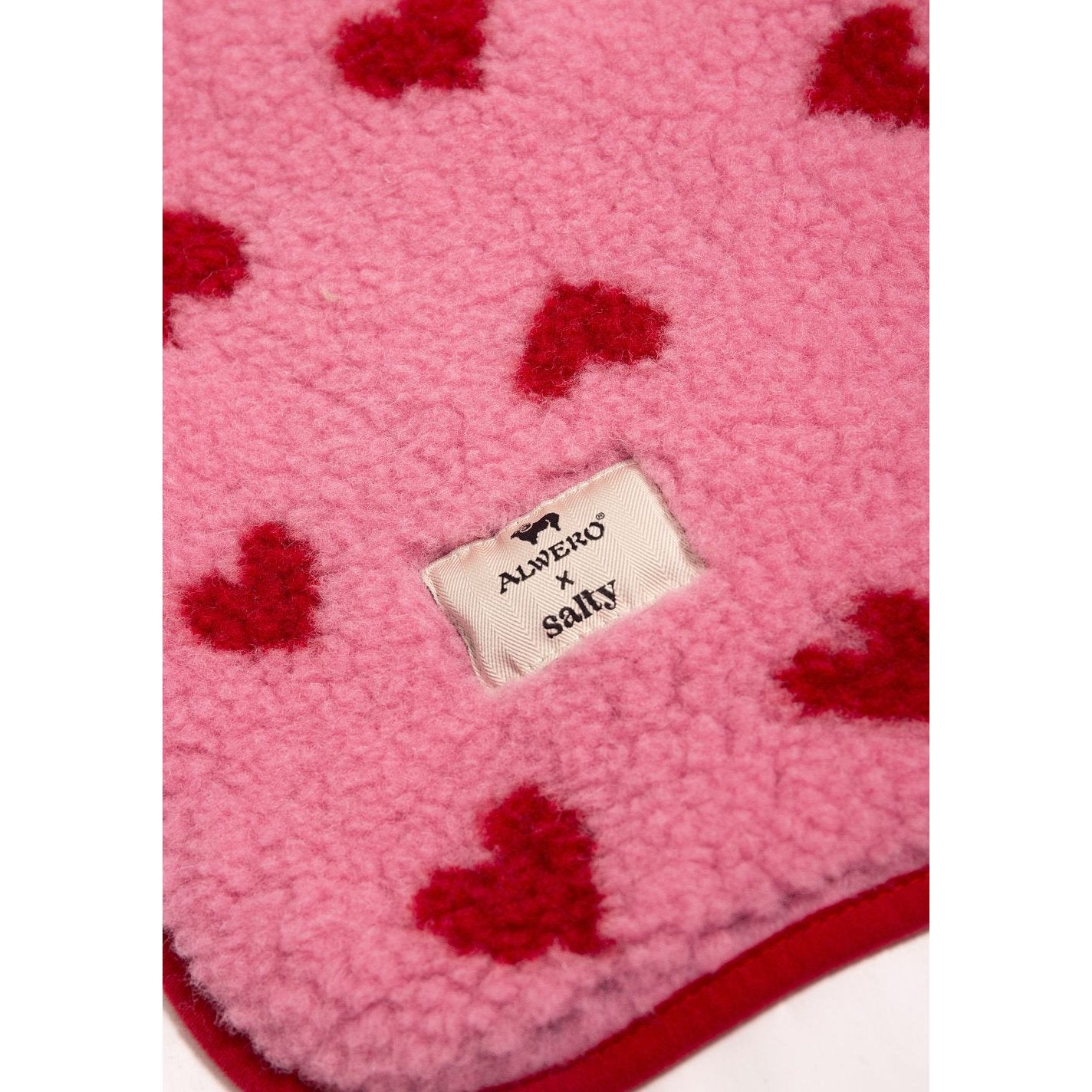 Alwero X Salty wollen deken in roze met rode hartjes patroon, close-up van label op textuur