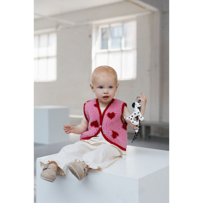 Alwero X Salty Lulu Baby bodywarmer roze met hartjes, gedragen door peuter op wit podium met speelgoed