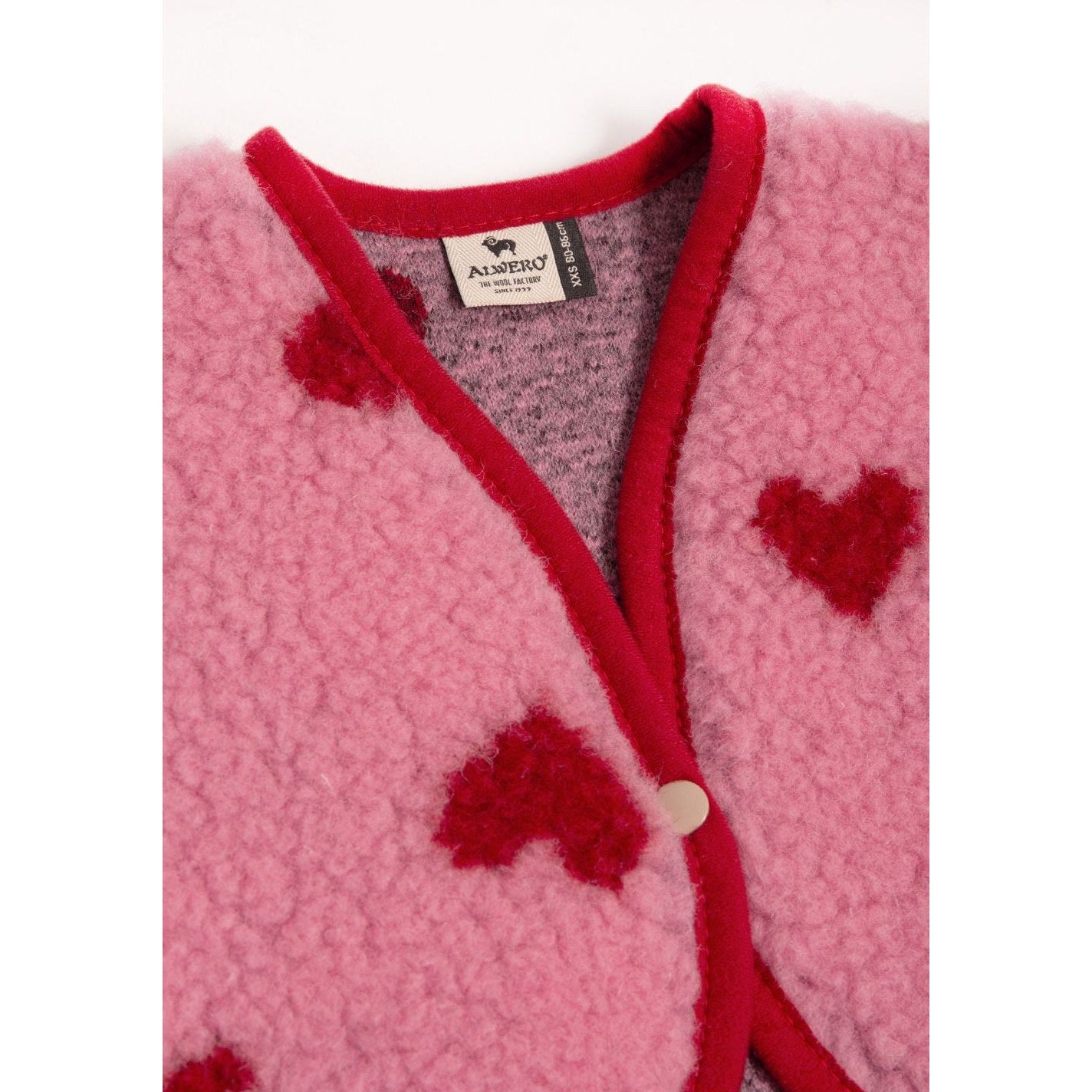 Alwero X Salty Lulu Baby bodywarmer in roze wol, bovenaanzicht met rode hartjes en bieding detail
