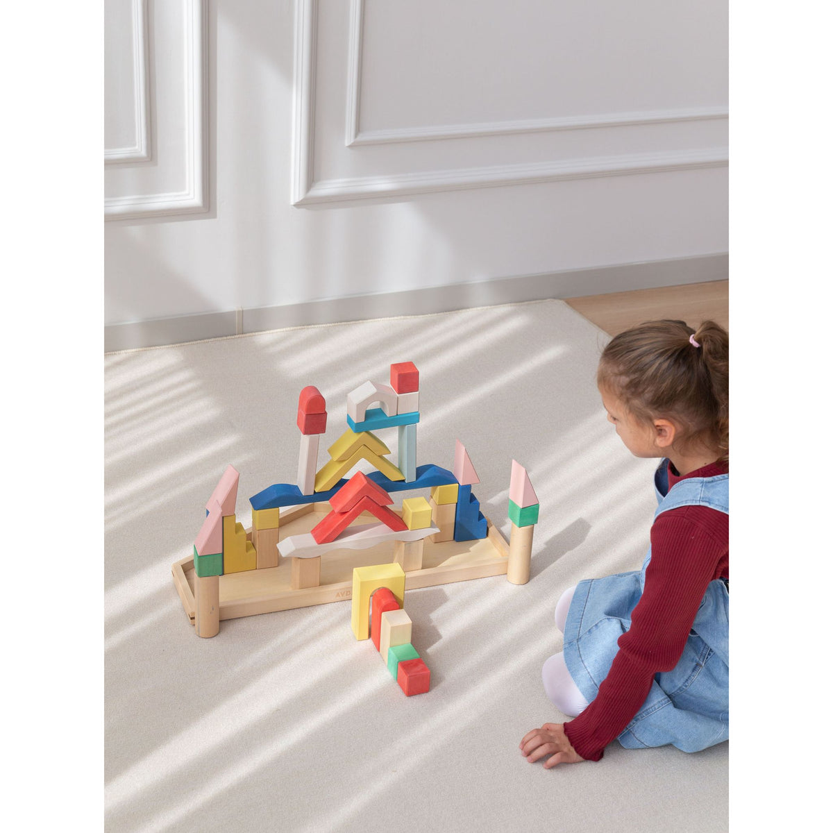 Avdar houten bouwblokken set met kleindochter spelend in zonnig interieur, bovenaanzicht