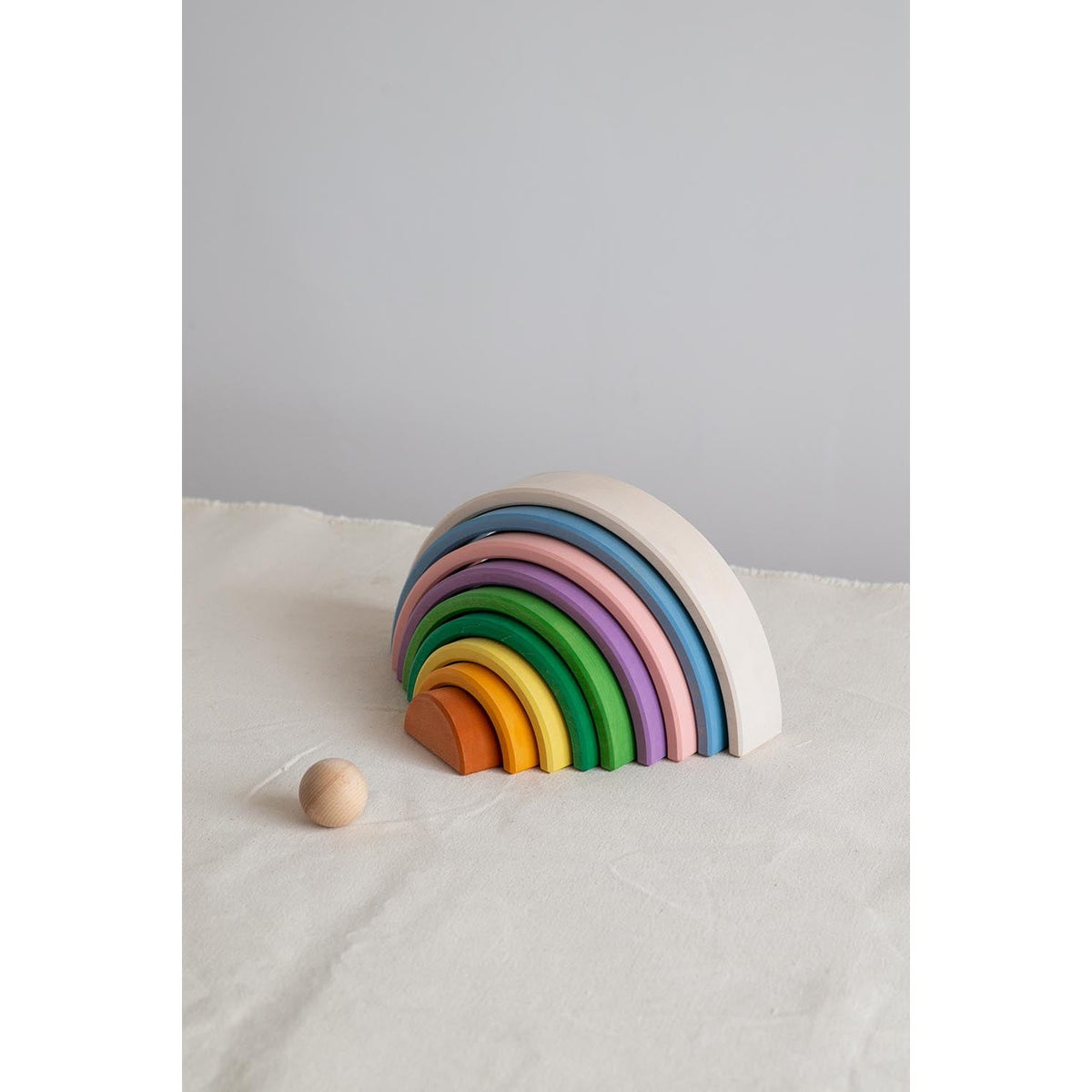 Avdar grote regenboog stacker met 12 gekleurde houten bogen en houten bal op zand, schuin perspectief