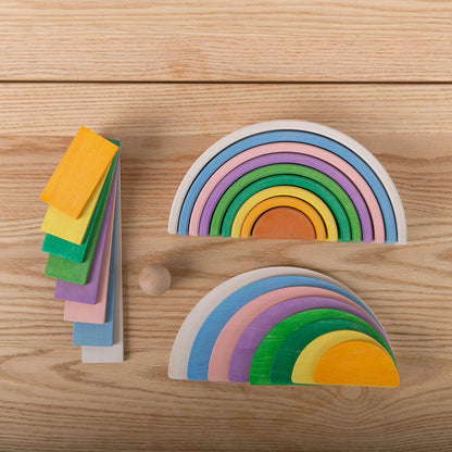 Avdar houten halve cirkels in pastelkleuren: twee halve maan boards staand, losse gekleurde blokken gestapeld, en houten bal op natuurhouten ondergron