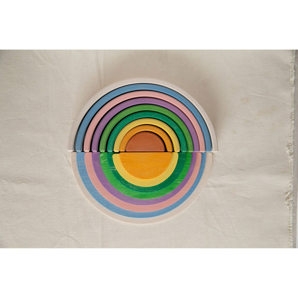 Avdar halve cirkels bouwset met regenboogkleuren gestapeld in cirkelpatroon, bovenaanzicht op beige ondergrond