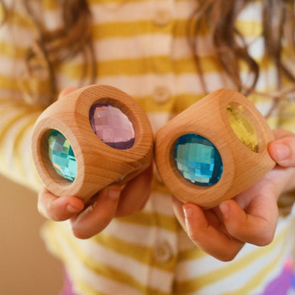 Bauspiel houten sensorische kubus met gekleurde facetgeslepen kristallen in kinderhanden