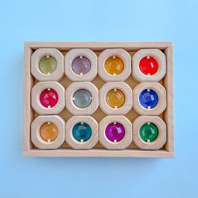 Papoose Toys houten sorteerdoos met 12 gekleurde kristallen in bovenaanzicht op blauwe achtergrond