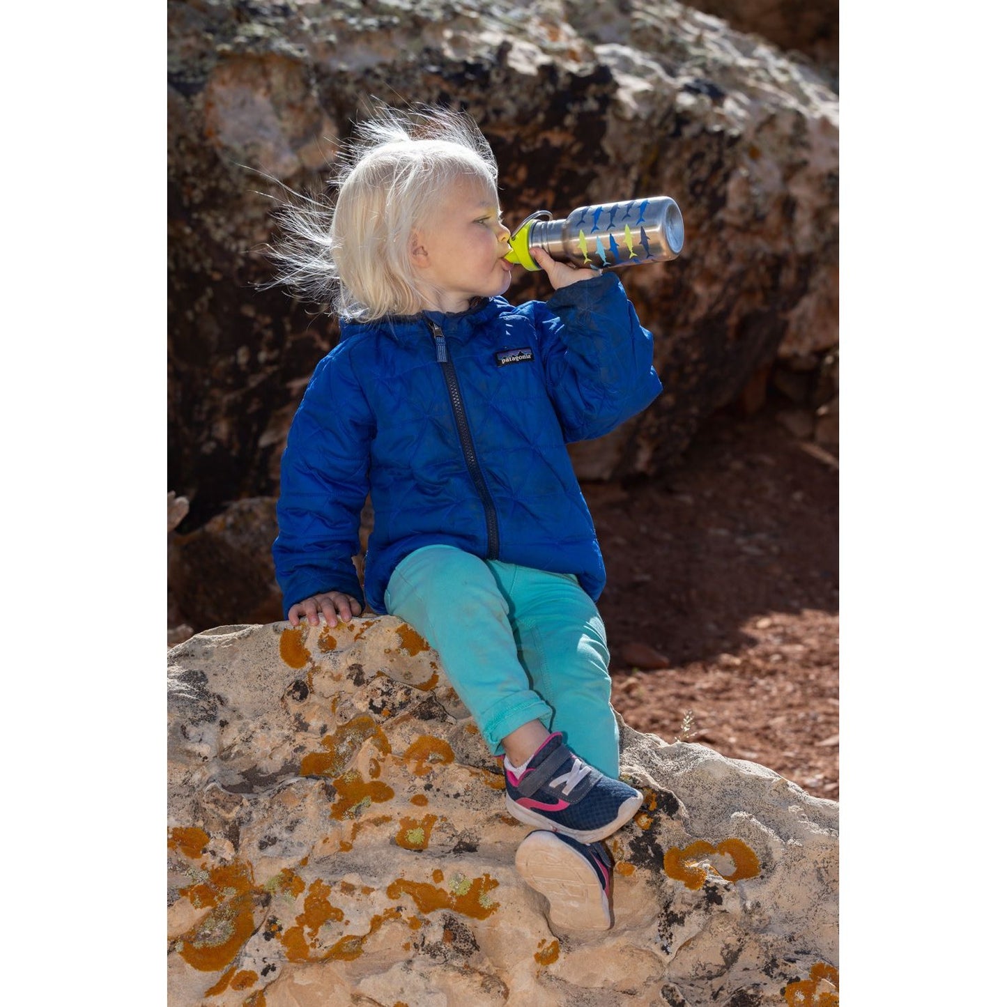 Klean Kanteen Classic 355ml sippy cup met unicorn print, gebruikt door peuter zittend op rots