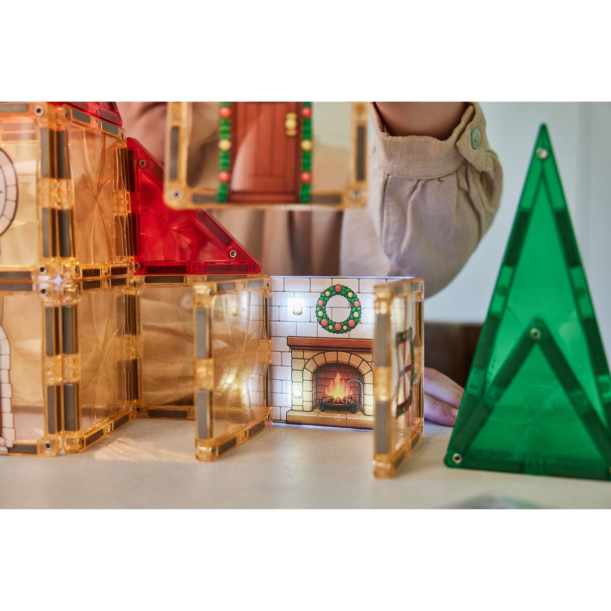 Cleverclixx Christmas Village adventskalender met magnetische tegels: huisje met open haard en kerstkrans, groene boom ernaast.