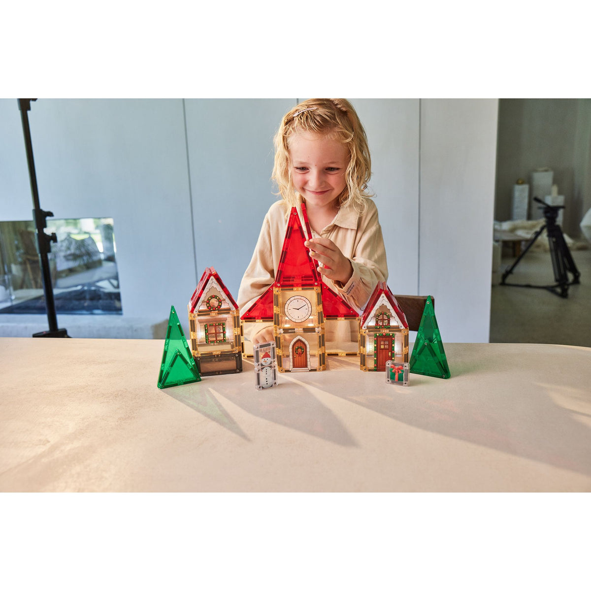 Cleverclixx Christmas Village adventskalender: kind speelt met verlichte magnetische tegels kersthuisjes op tafel