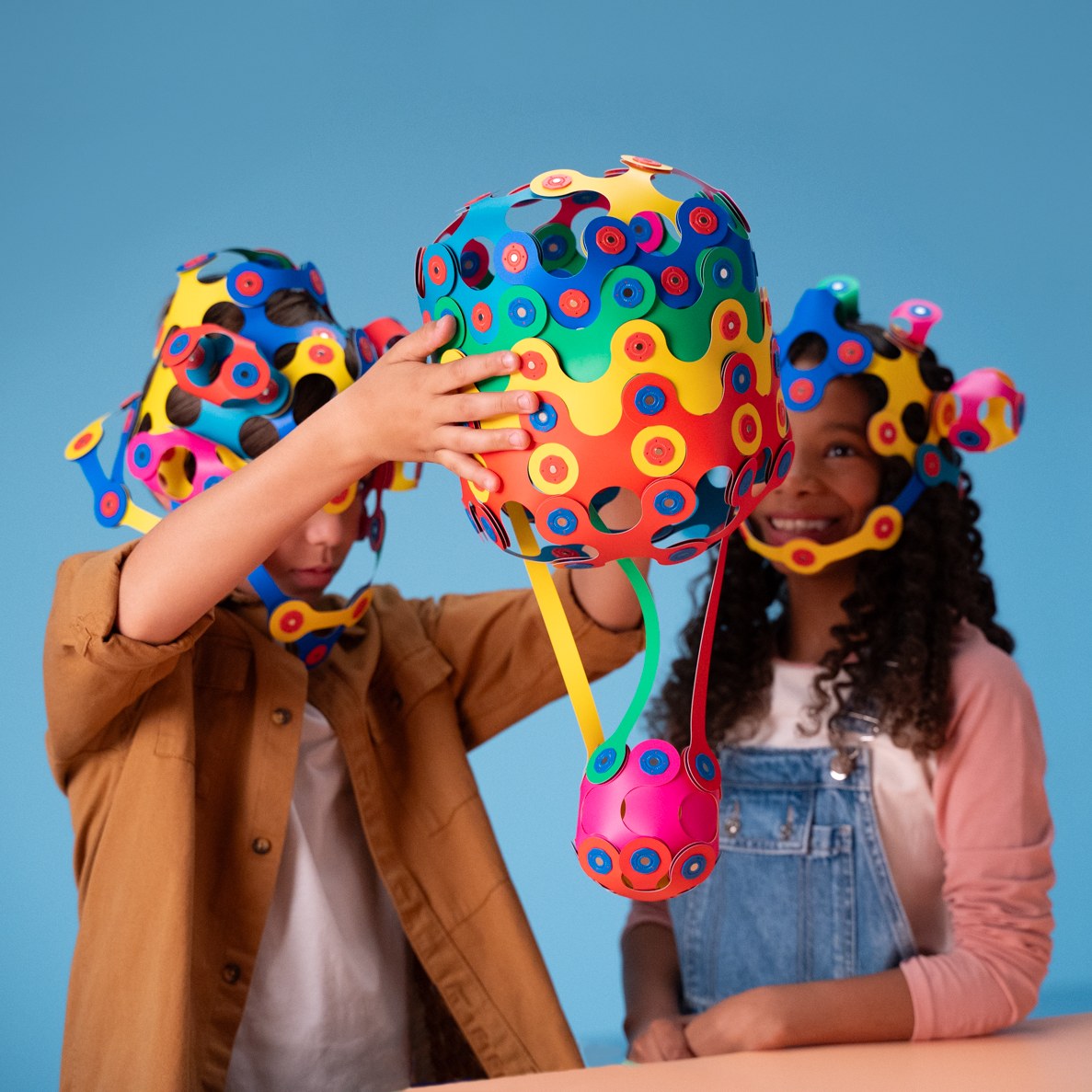 Clixo Family Pack magnetisch bouwspeelgoed: kinderen houden gekleurde 3D-ballen omhoog tegen blauwe achtergrond