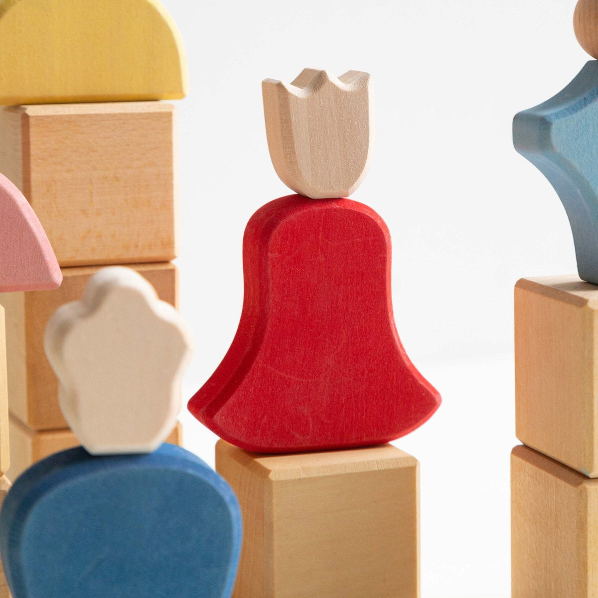 Avdar Fairytale Family houten figuren: diverse poppen met rode jurk en houten toppen, gestapeld op blokken.
