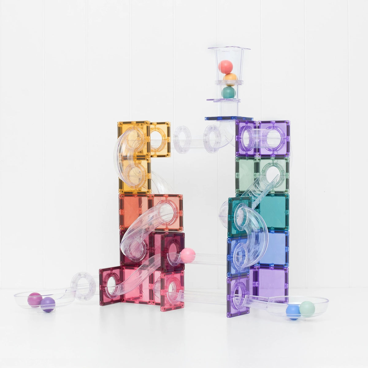 Connetix magnetische balbaan in pastelkleuren: twee torens met buizen en gekleurde balletjes, frontaal zicht op de constructie