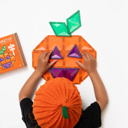 Connetix magnetische tegels Halloween Pumpkin Pack: kind bouwt pompoen-gezicht met paarse en groene driehoeken op oranje basis
