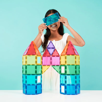 Connetix magnetische tegels: meisje bouwt kleurrijk kasteel met torens, kijkt erdoorheen met blauw spiegelstuk