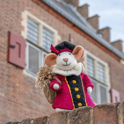 Sjaal met Verhaal Pietermuis in cyclaamrood piet kostuum met zwart jasje, frontaal gefotografeerd tegen bakstenen huisachtergrond