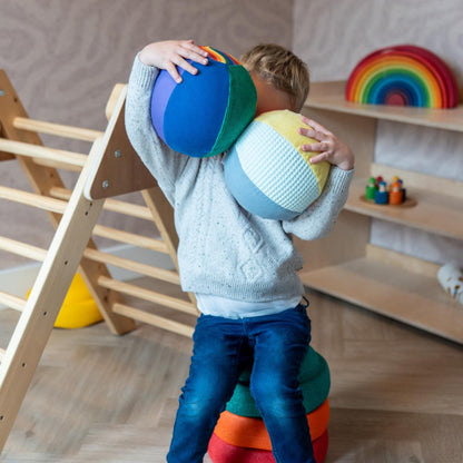 Little Botanic Label sensorische ballonbal - kind houdt gekleurde ballonbal voor gezicht in speelkamer met houten meubels