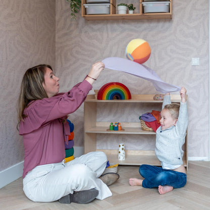 Little Botanic Label sensorische ballonbal in gebruik: moeder en kleuter spelen samen met de zachte stoffen bal in een speelkamer met houten speelgoed