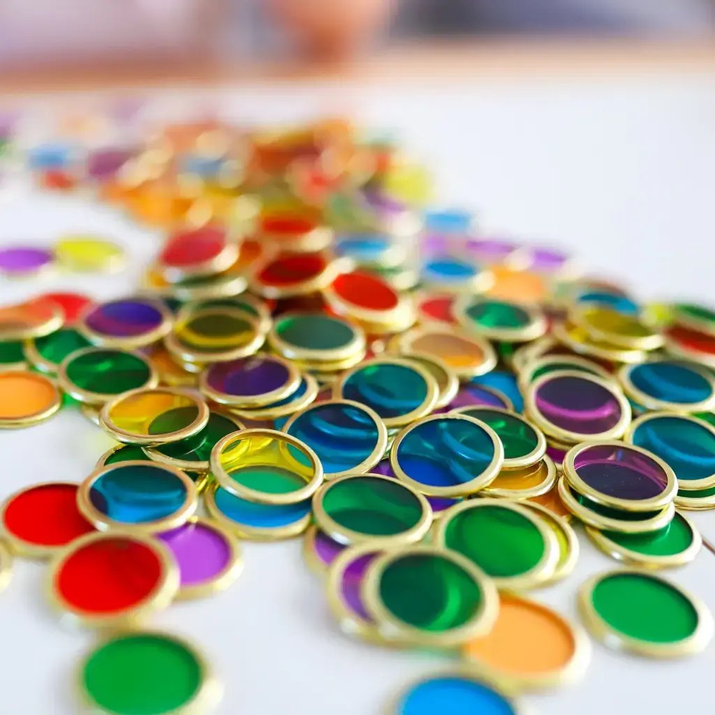 Learn and Grow Toys magnetische wand chips - 100 gekleurde transparante ringen met metalen rand, close-up detail van verspreide kringeltjes op wit opp
