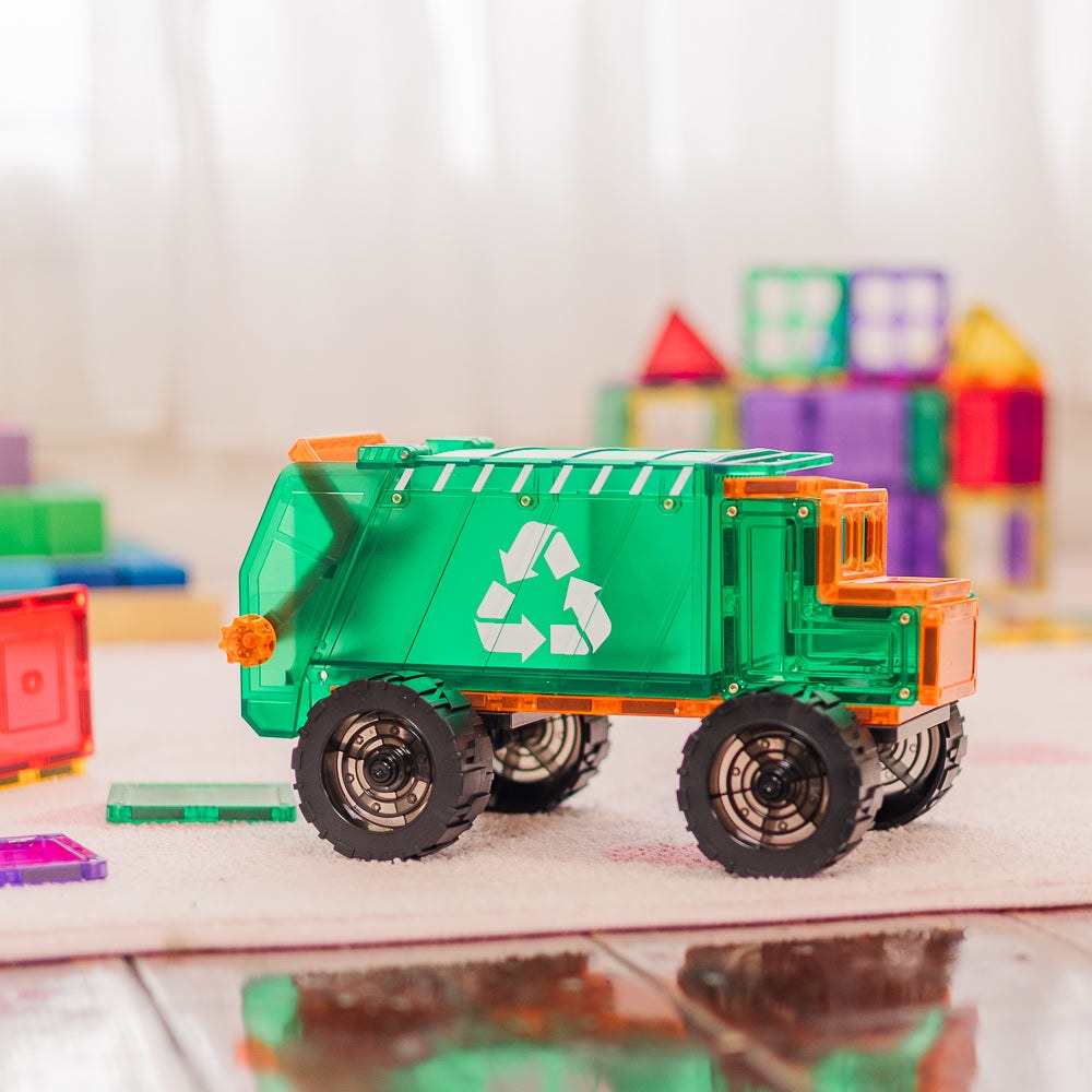 Learn & Grow magnetische recycling truck speelgoed met groen lichaam en oranje details, vooraanzicht op houten vloer tussen gekleurde bouwblokken