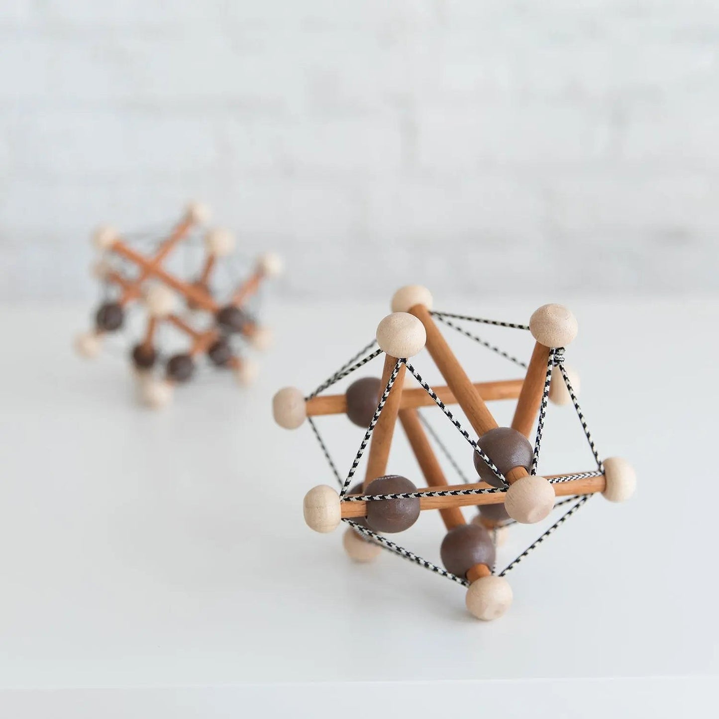 Manhattan Toy Skwish Artful rammelaar in close-up: houten constructie met elastische koorden en glijdende kralen, vooraanzicht met tweede speelgoed on