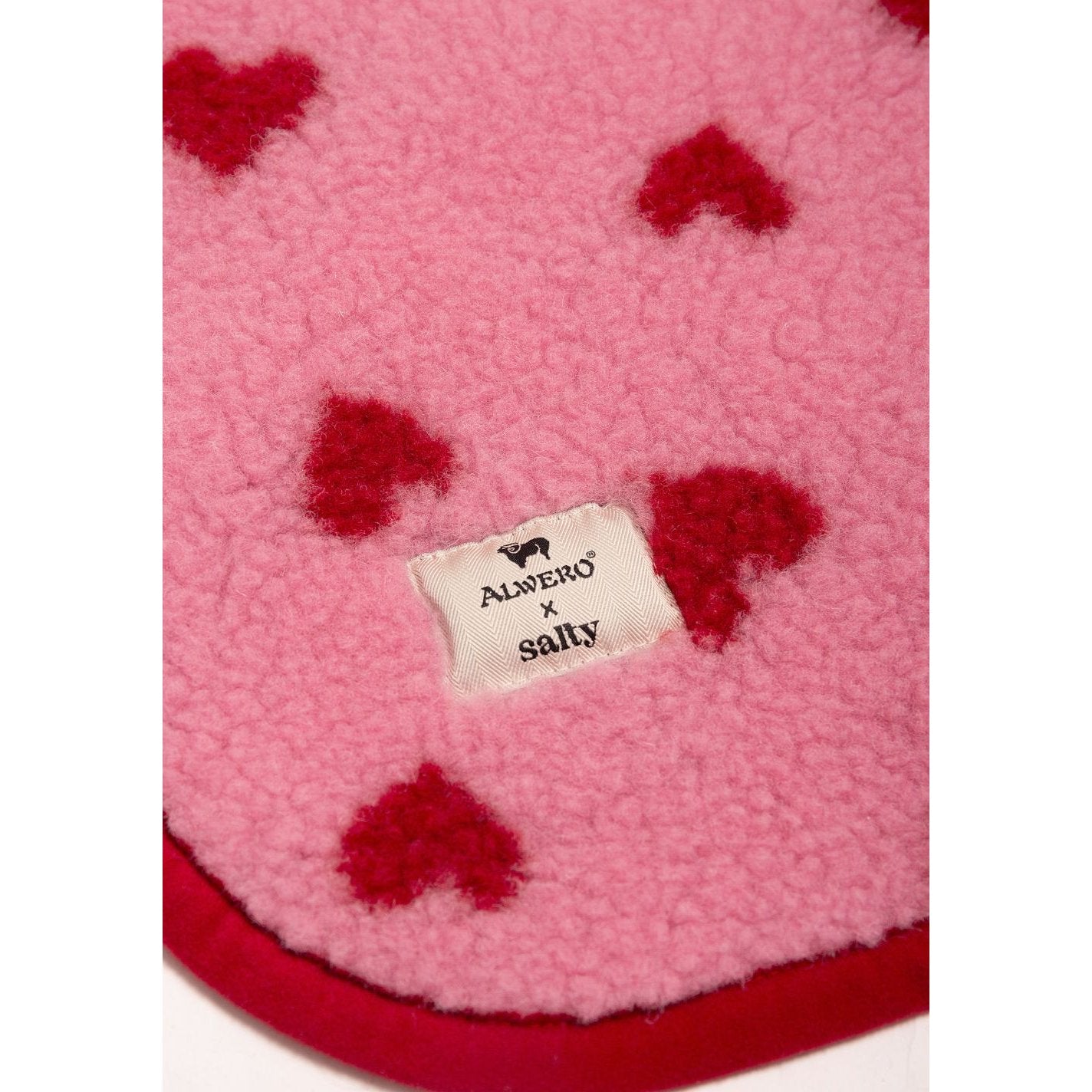 Alwero X Salty wiegbeschermer in roze wol met rode hartjesprint, bovenaanzicht met etiket zichtbaar