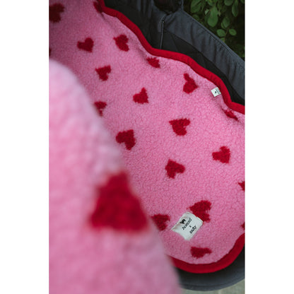Alwero wiegbeschermer in roze wol met rood hartjespatroon, detail van de matrasbeschermer met labels zichtbaar