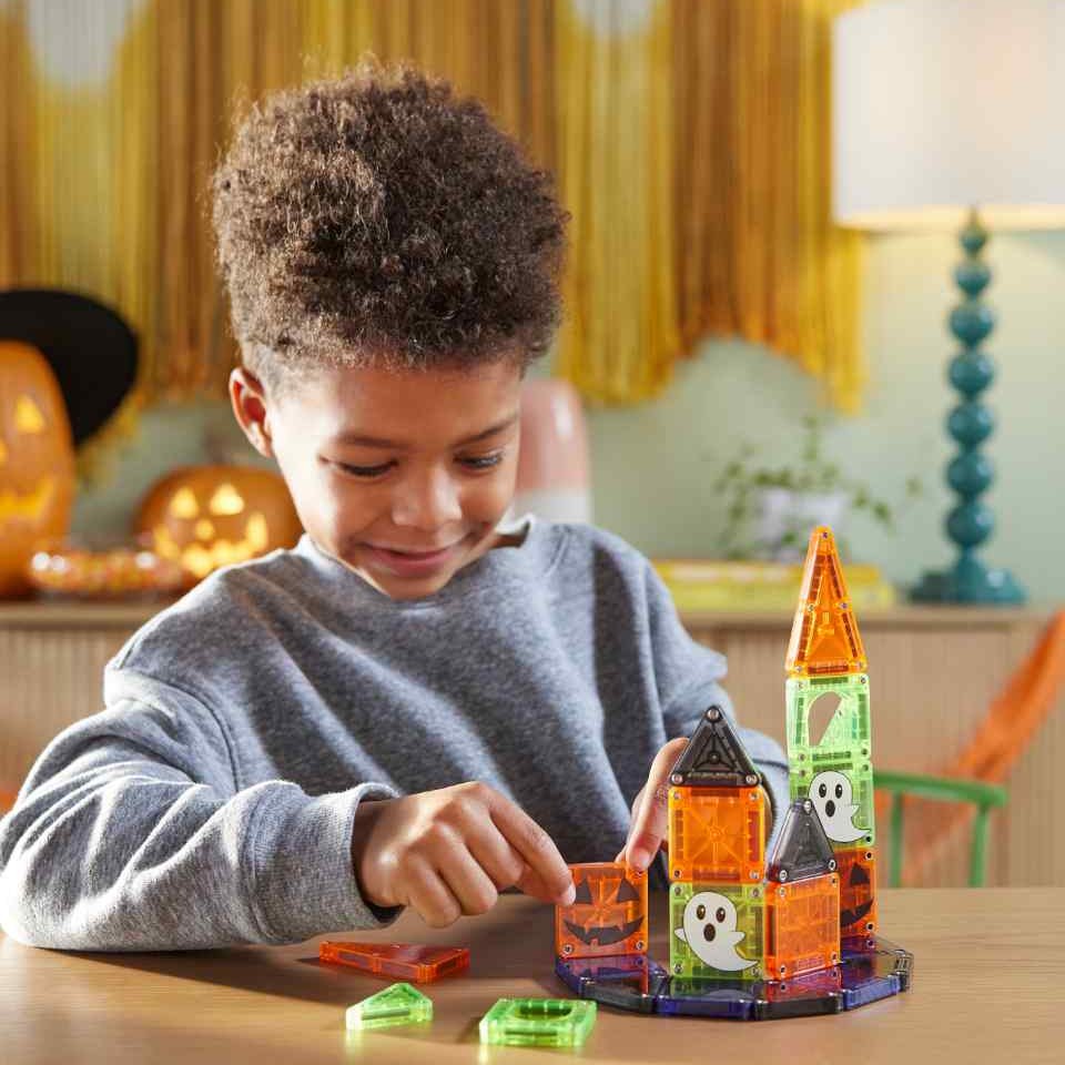 Kind bouwt spookachtig kasteel met Magna-Tiles MicroMAGS Travel set, magnetische tegels in oranje en groen