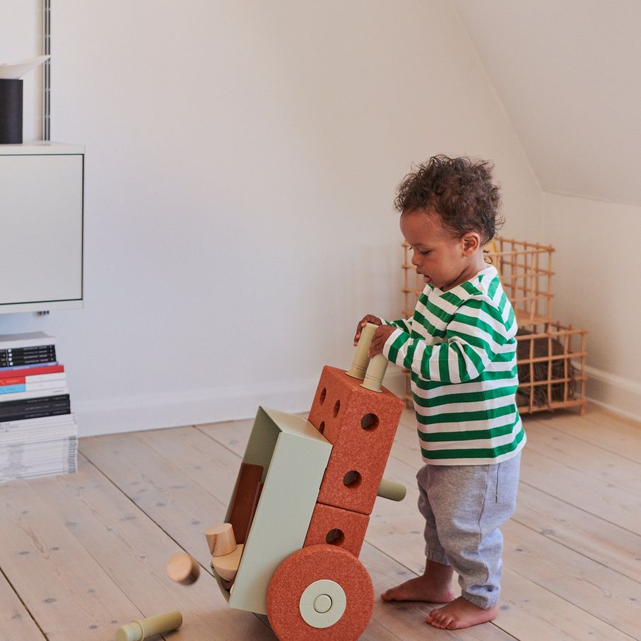 MODU 3-in-1 Baby Walker in Burnt Orange met kleuter die loopwagen voortduwt in minimalistisch interieur