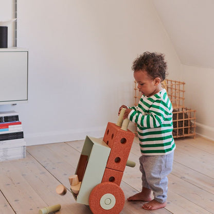 MODU 3-in-1 Baby Walker in Burnt Orange met kleuter die loopwagen voortduwt in minimalistisch interieur