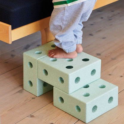 MODU baby walker Ocean Mint: peuter in groen-wit gestreept shirt staand op de schuimblokken van de 3-in-1 loopwagen, vooraanzicht op houten vloer