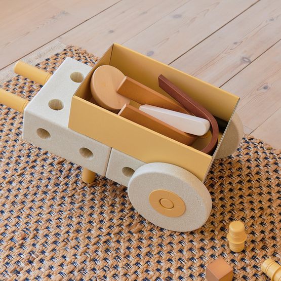 MODU 3-in-1 babywalker in sand grey en honey yellow, bovenaanzicht met speelgoed in het bakje, op geweven tapijt