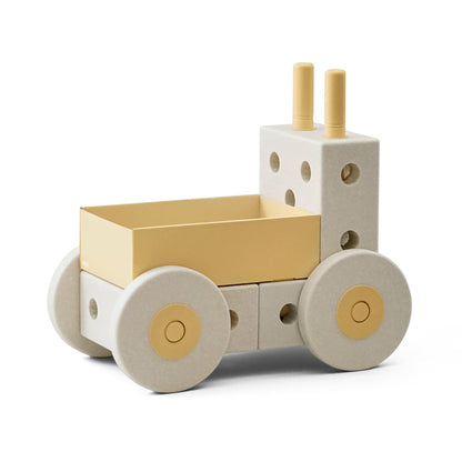 MODU 3-in-1 Babywalker in sand grey en honey yellow, aanzicht van voren met gele laadkak, wielen met gouden accenten en witte kubusvormige blok achter