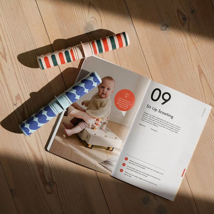 MODU Baby Activity Set Deep Blue met gekleurde speelelementen en instructieboekje op houten vloer in zonlicht