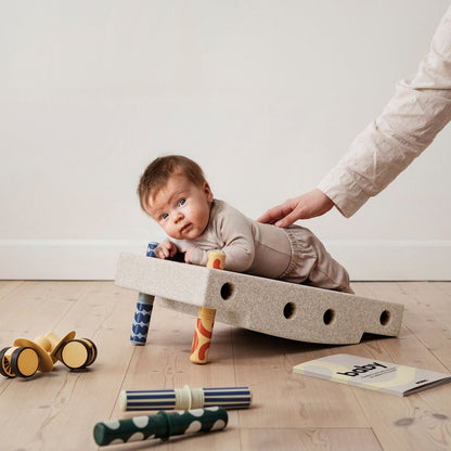 MODU Baby Activity Set Sand Grey met baby die speelset verkent, omringd door speelgoed op houten vloer