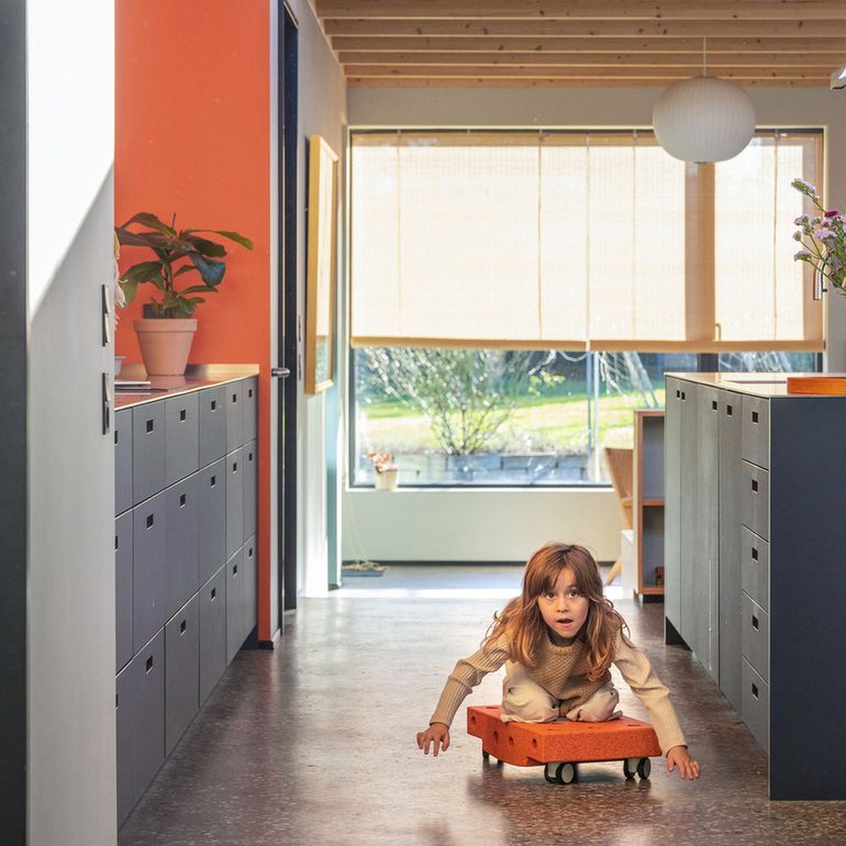 MODU Curiosity Set: meisje speelt in modern interieur met oranje rijdend blok tussen grijze kasten