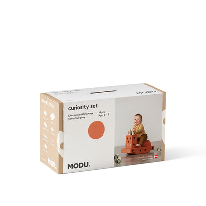 MODU Curiosity Set verpakking met afbeelding van peuter spelend met oranje bouwstenen op witte achtergrond