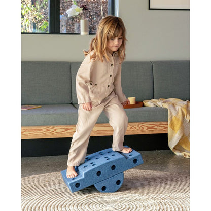 Kind balanceert op MODU Curiosity Set bouwblokken in woonkamer, ontwikkelt evenwicht en coördinatie